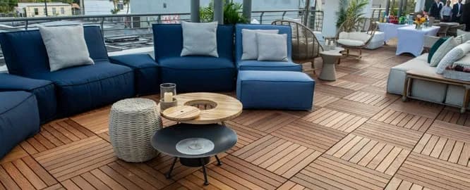 Square wood deck tiles laid in alternating directions beneath blue outdoor lounge seating