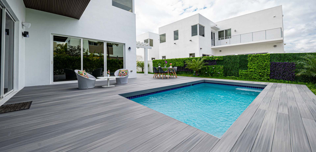 Light-gray composite decking surrounding a pool in the backyard of a modern house
