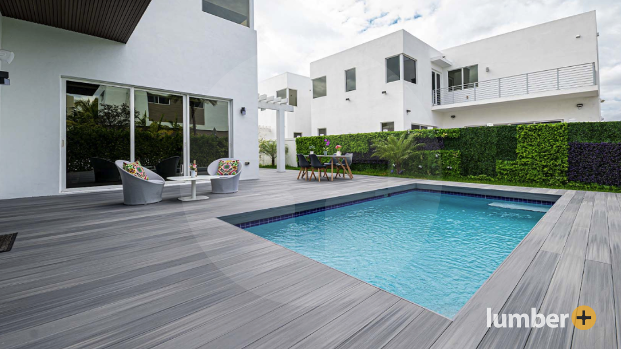 Light gray decking next to a house’s small square pool.