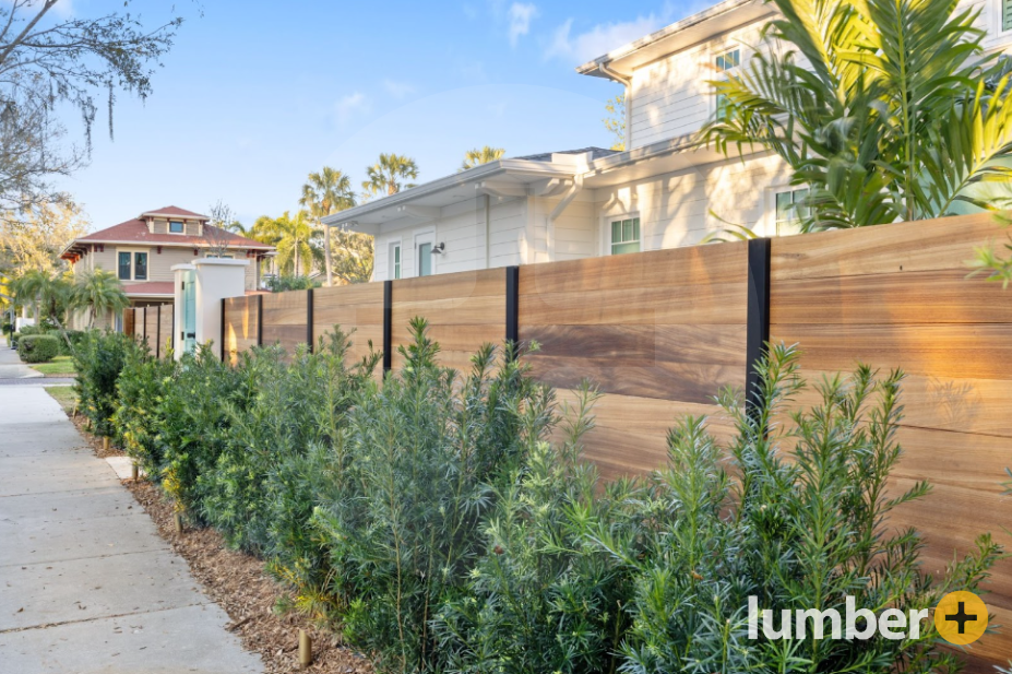 Light wooden privacy fence separating a house from the sidewalk.