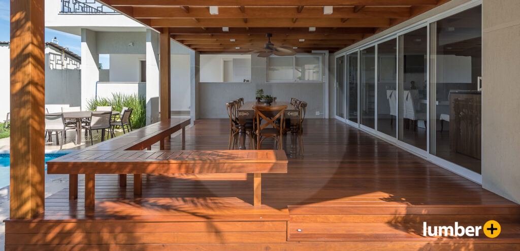 Warm wooden decking in an open air dining area on the porch of a house.