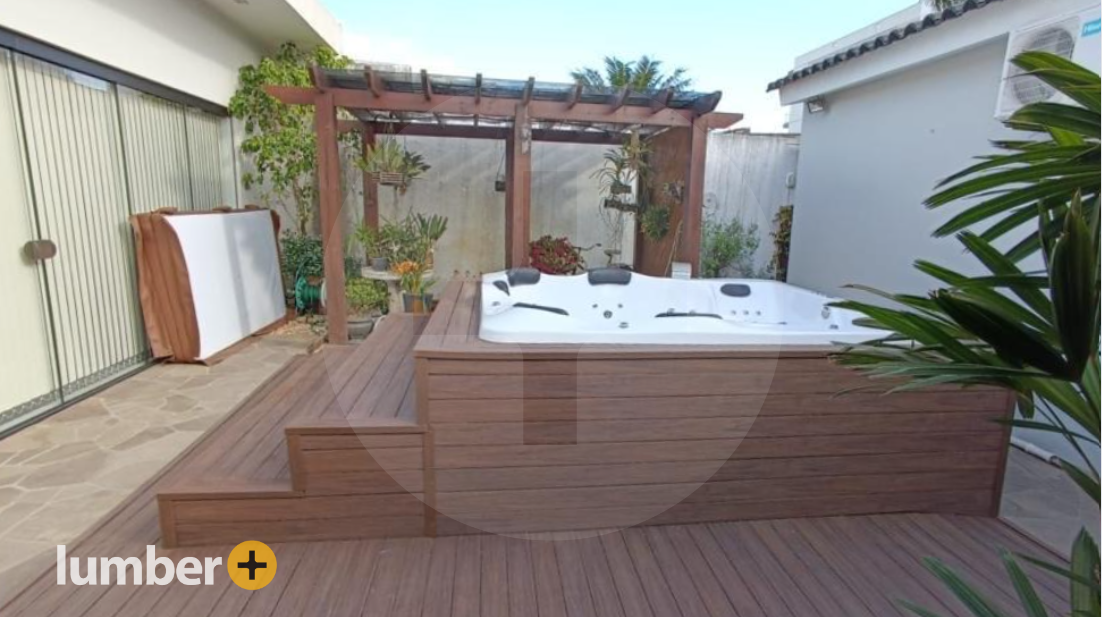 Wood cladding deck surrounding a hot tub in the backyard with a pergola.