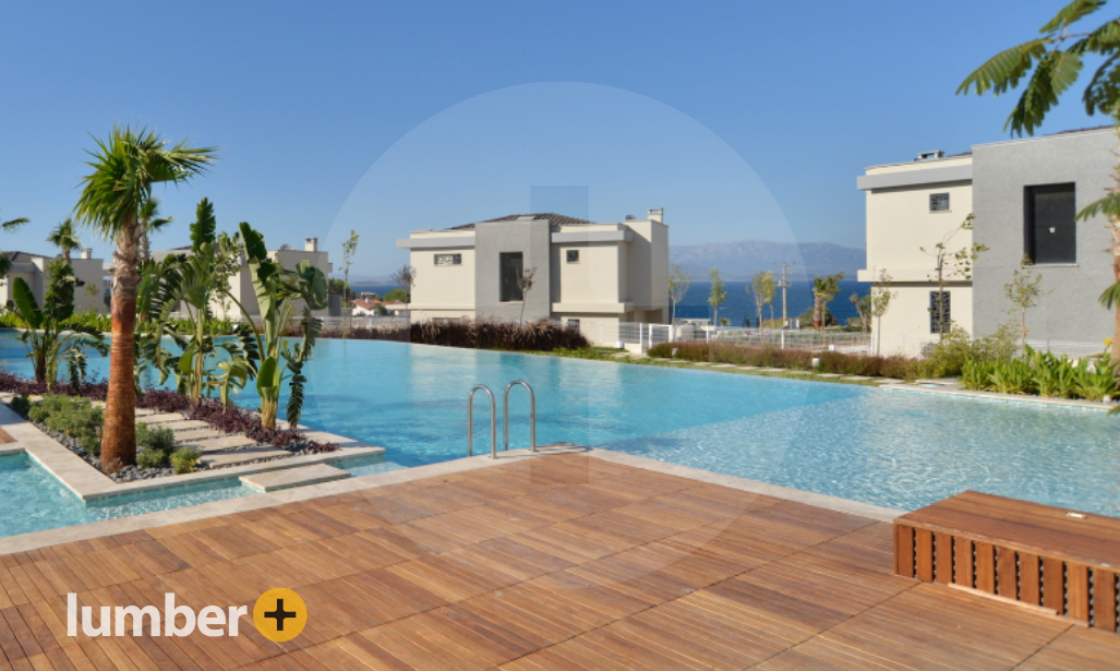 A luxurious pool with a wooden lounge deck. 