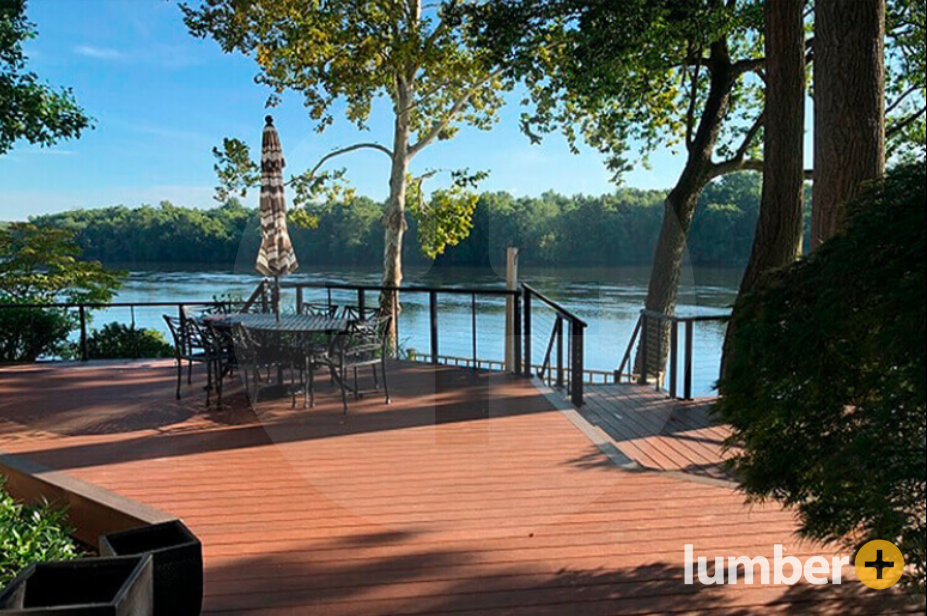 A brown PVC deck with a dining table overlooking a large lake.