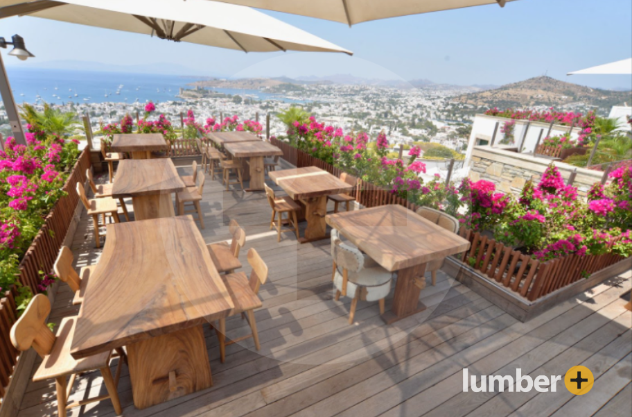 Outdoor restaurant overlooking the coastline with wooden tables and decking.