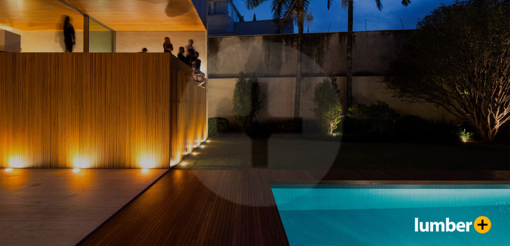 Wood cladding lines the exterior walls of a house next to a swimming pool. 