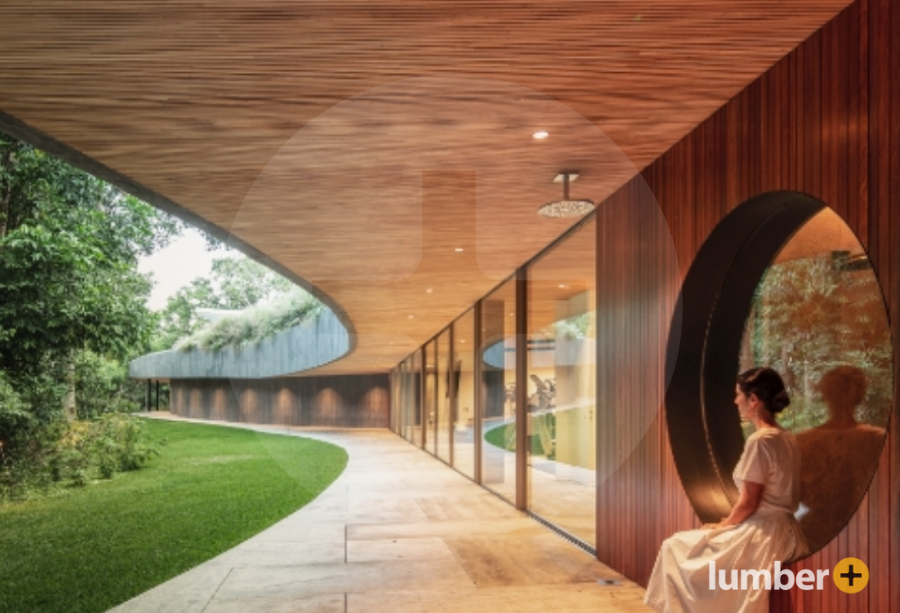 Woman sits outside a building with a wood clad exterior.