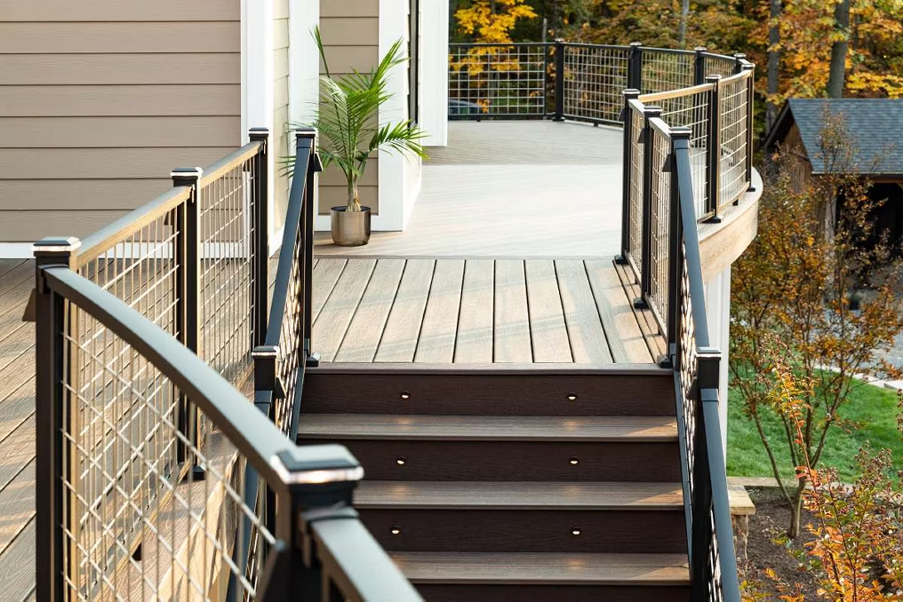 Black Trex railing with light top caps, mesh infill, and a curved design for a smooth, flowing transition.