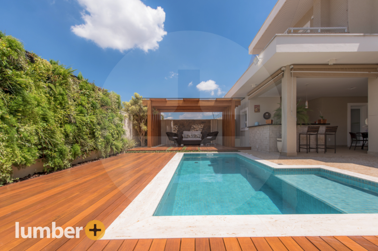 Golden hardwood around a pool offers an elegant ground level deck idea.