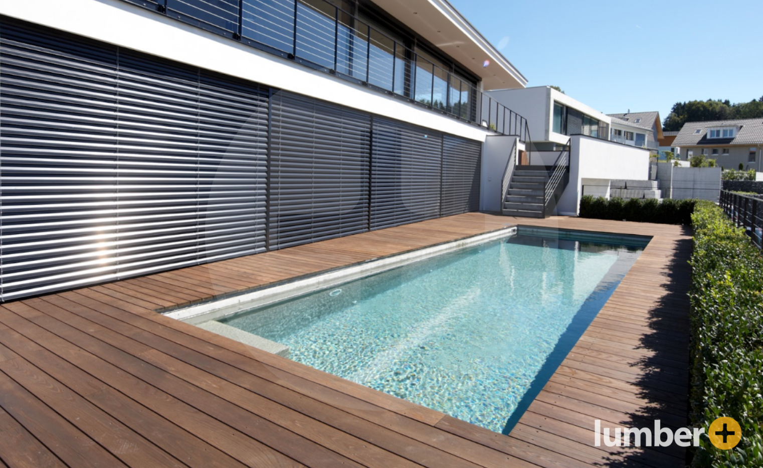 Wood-toned composite decking is a sleek ground level deck idea for a pool.