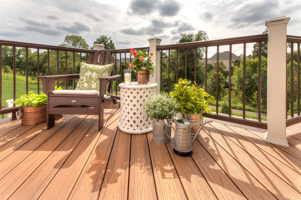 Light-colored Trex composite decking with patio furniture under bright sunshine.