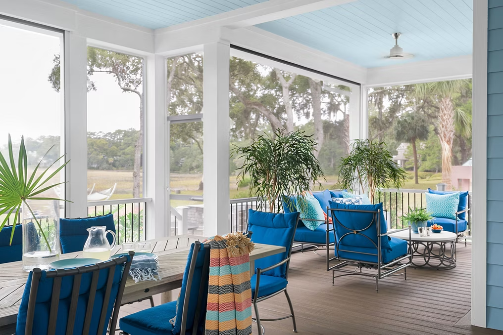 Enclosed patio featuring Trex decking in Coastal Bluff and white railing, decorated with bright blue cushioned furniture for a beachy atmosphere.