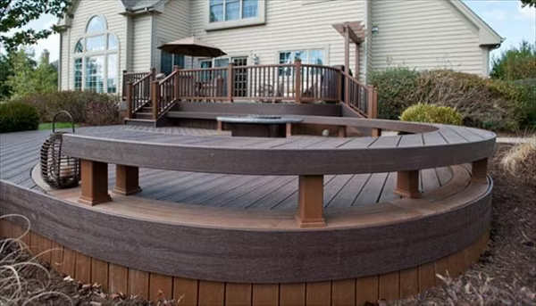 Dark brown Trex Transcend® curved fire pit deck with a matching curved bench for a cohesive design.