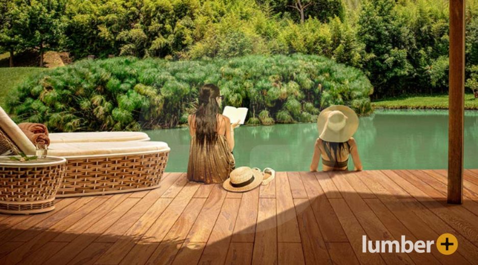 Two women sit on an outdoor wood deck enjoying the sun. 