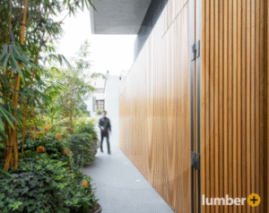 Modern walkway with vertical Cumaru wood cladding and lush plants.