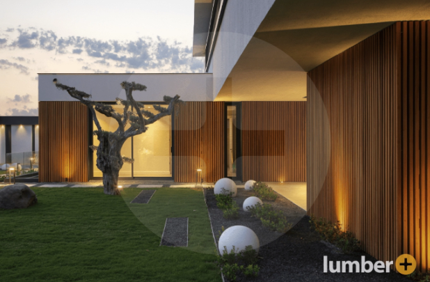 An image of a modern home with vertical wood slat siding and landscape lighting.