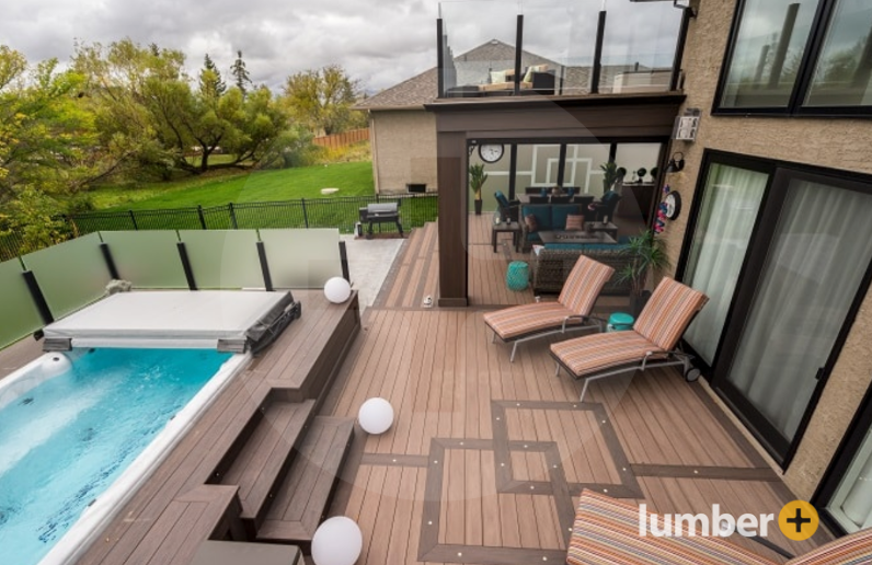 An image of a modern backyard with a patterned Fiberon deck, pool, and lounge seating.