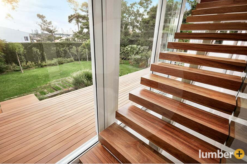 An image of floating Cumaru wood stairs beside a large window overlooking a backyard deck