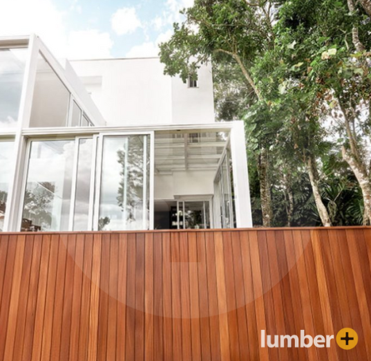 An image of a white modern home with glass walls and rich vertical wood siding along the base.