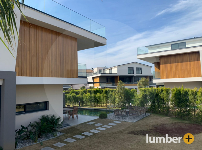 An image of modern homes with vertical wood siding and rooftop glass railings.